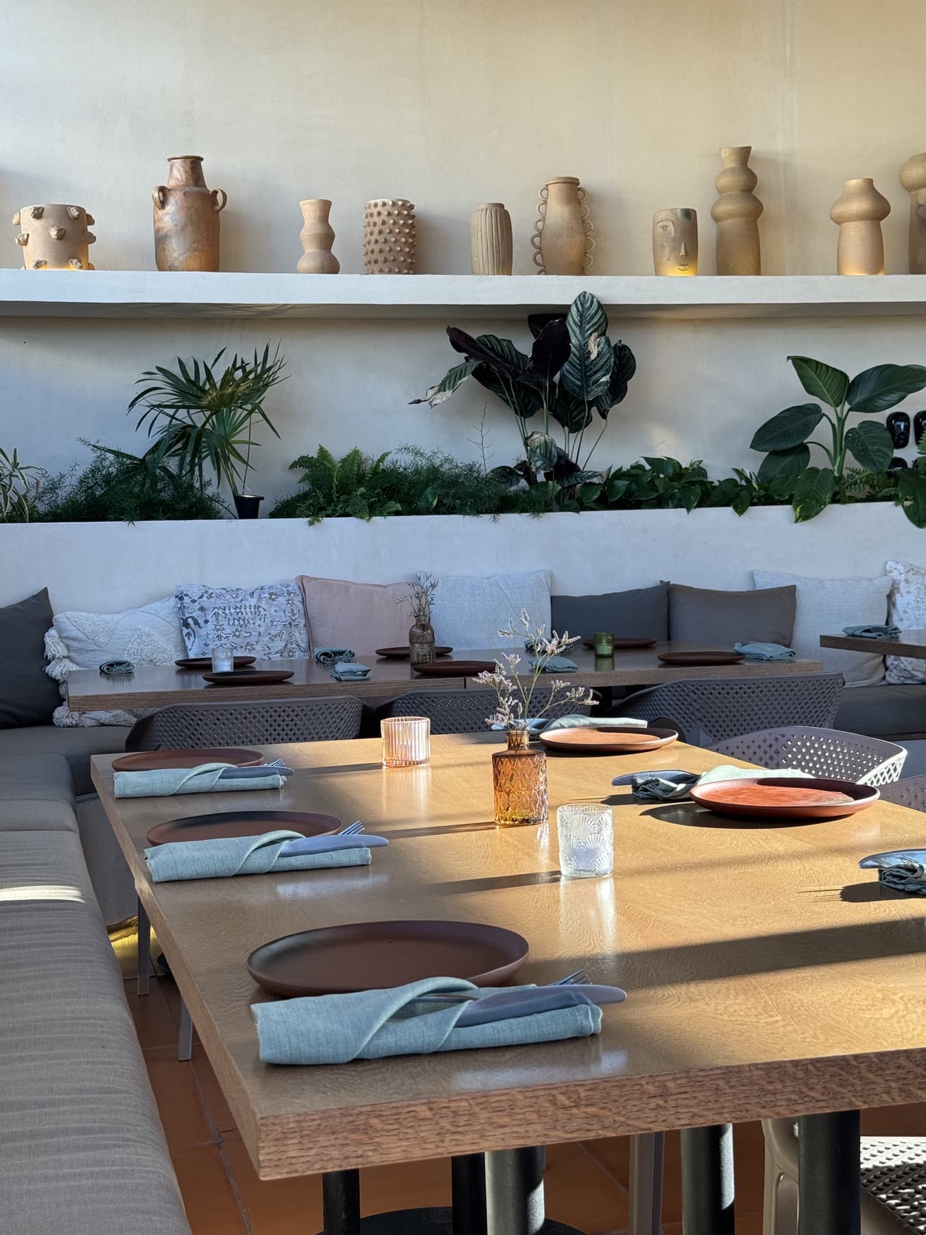 Earth-toned dining table with ceramics, greenery, and soft natural light