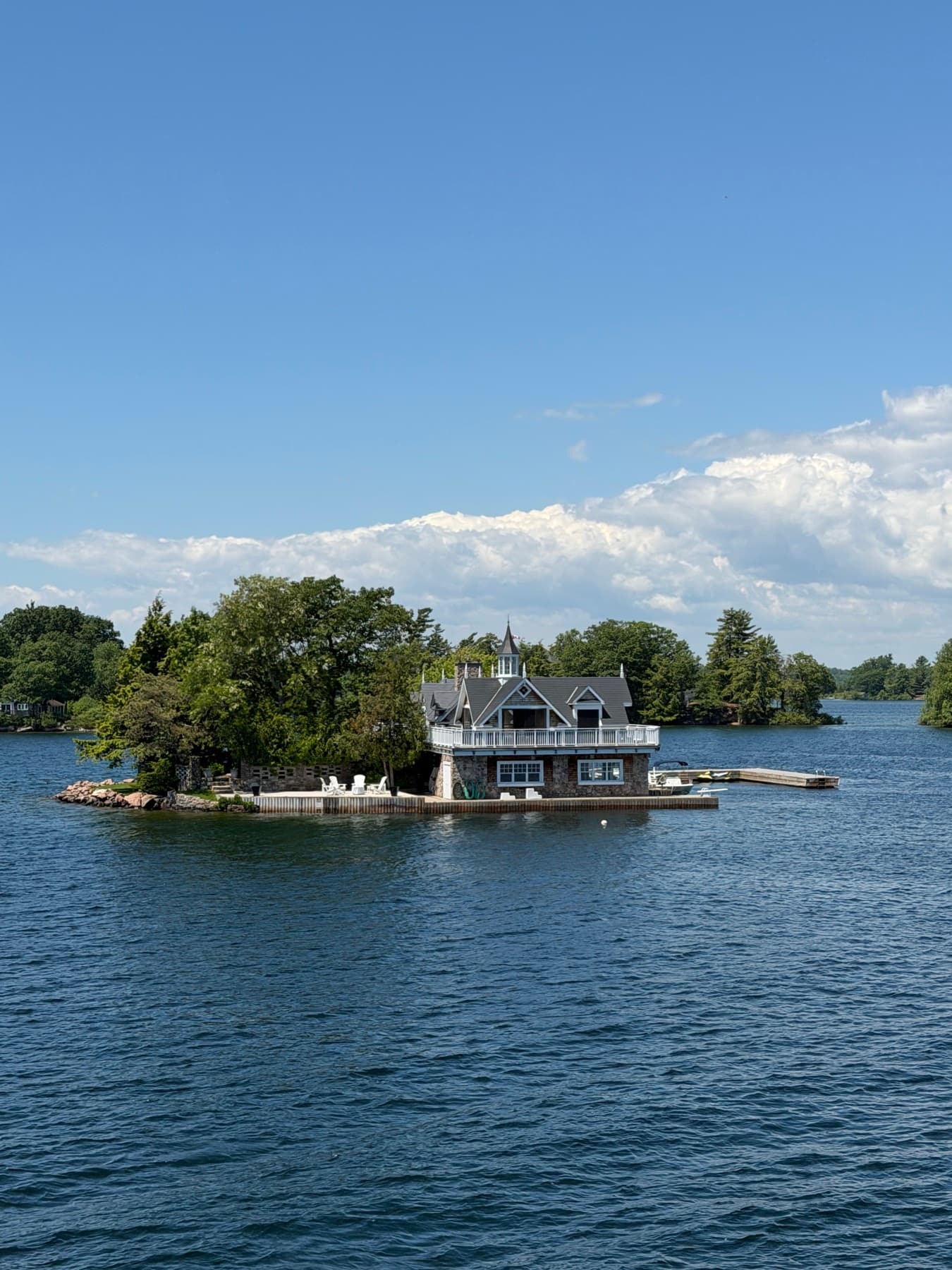 House on a tiny private island with Adirondack chairs along the dock