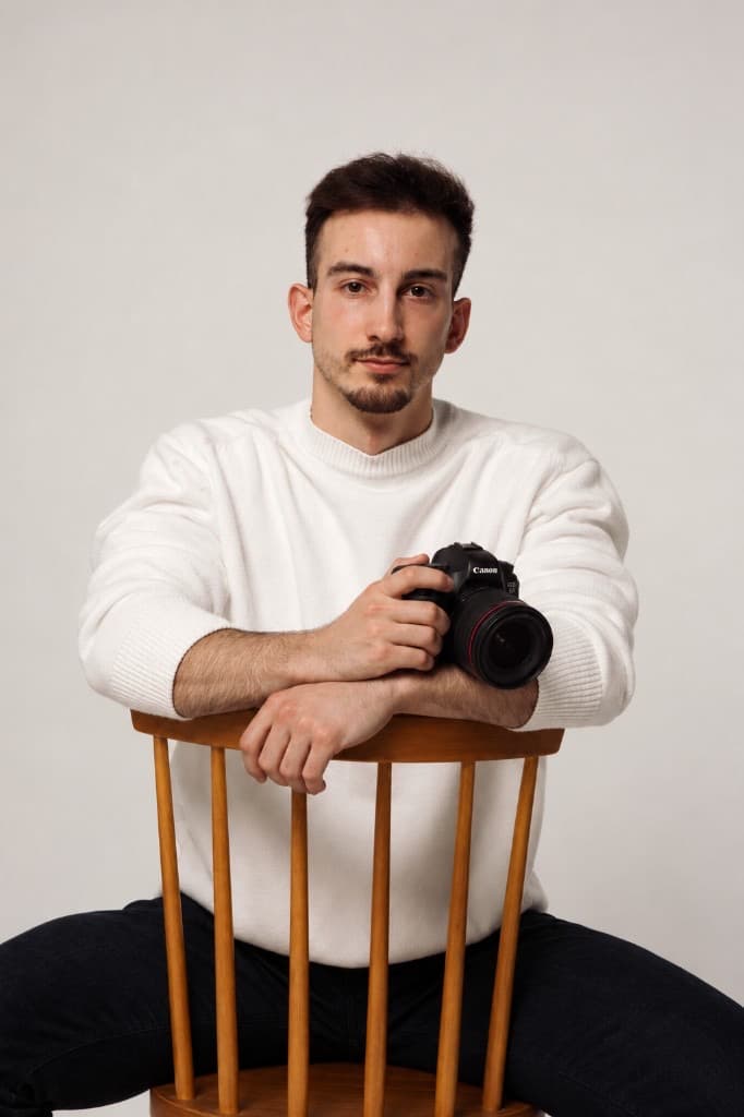 Michael seated with a camera in a soft studio portrait