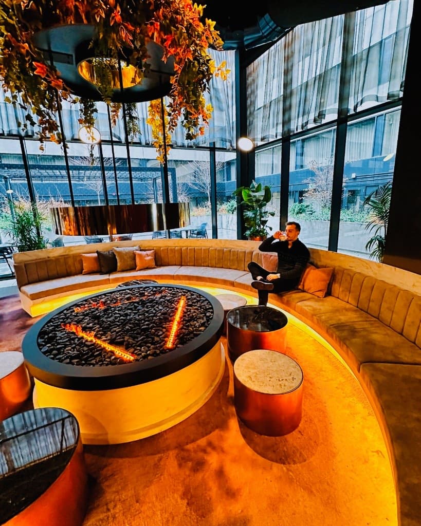 Michael seated in a curved lounge beside a circular fire feature